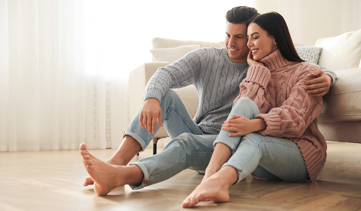 Happy-couple-sitting-on-wood-floor-in-living-room